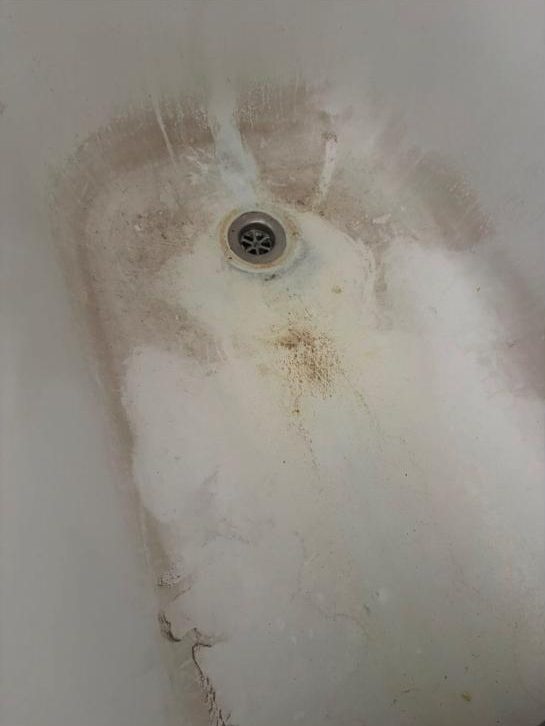 Bathtub with built-up soap scum and stains before cleaning